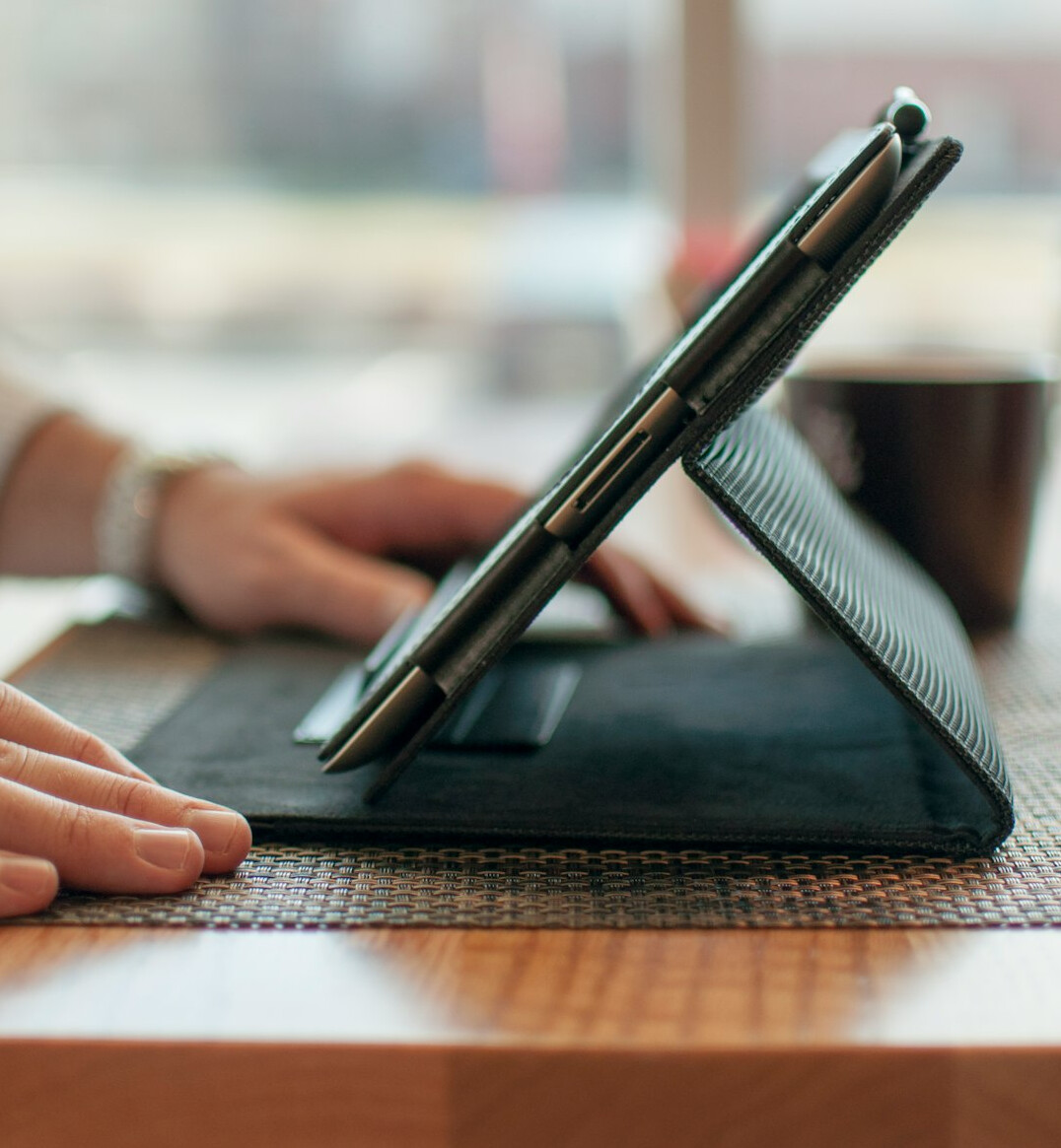 Hands typing on a laptop keyboard on a wooden desk
